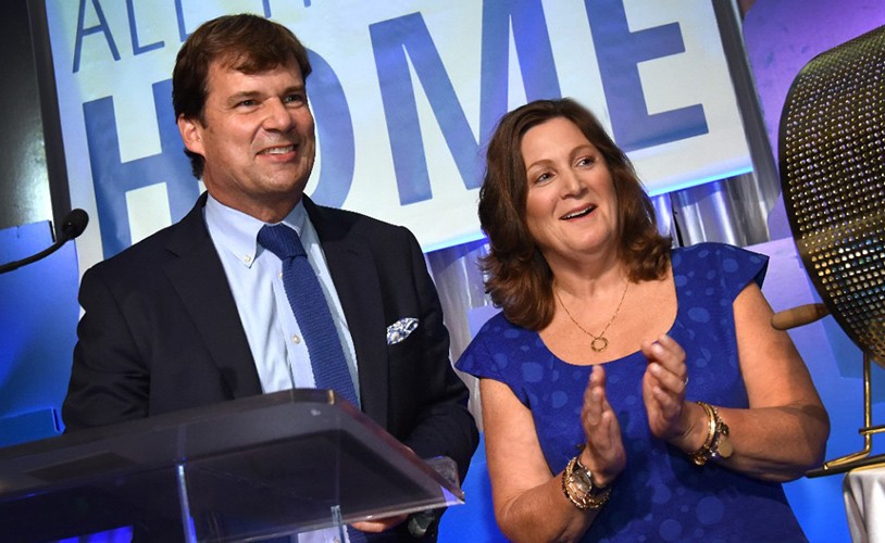 Jim Farley and Elena Ford smiling and clapping at a podium