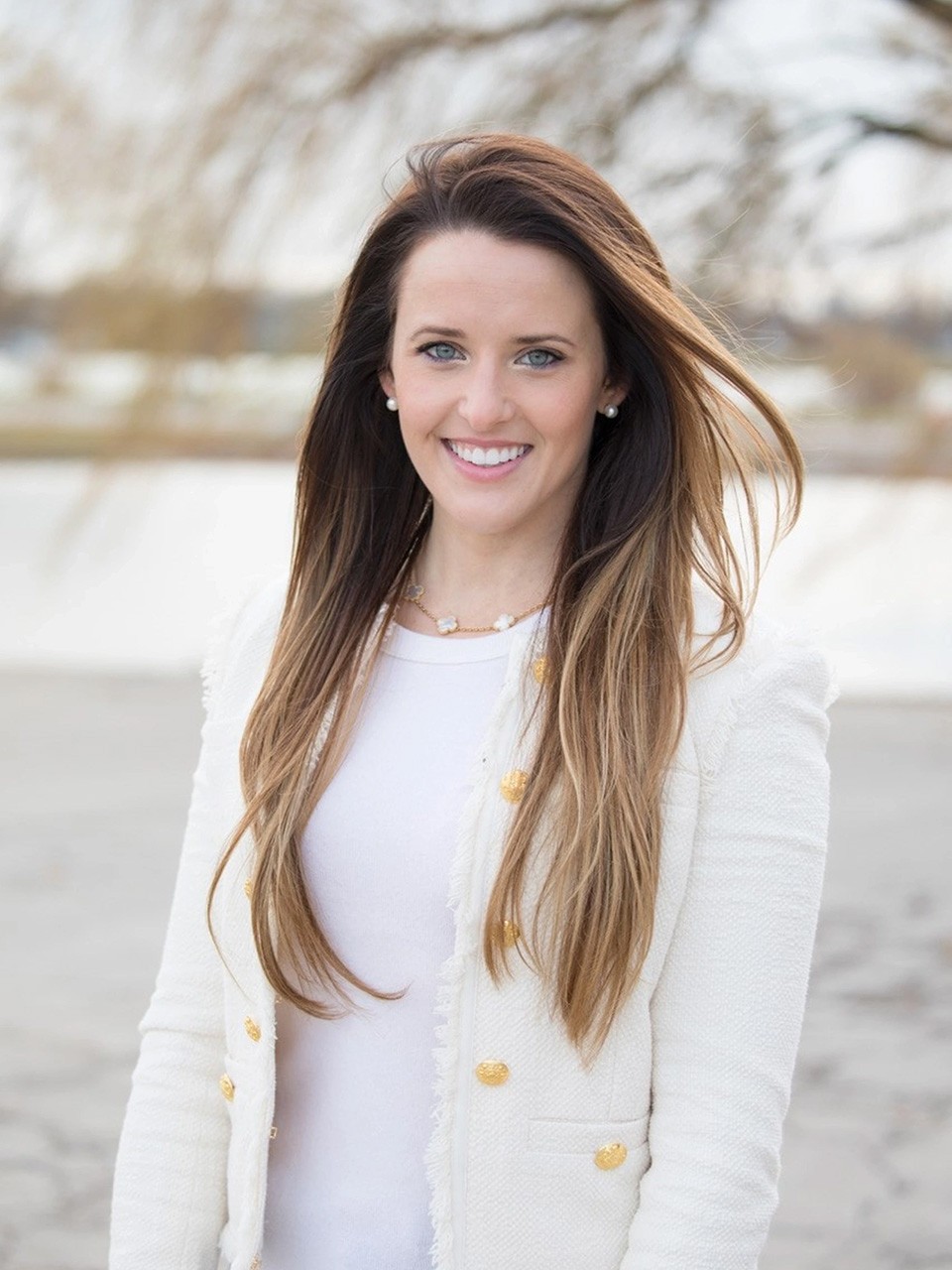 Alexandra Ford English stands in front of a lake smiling