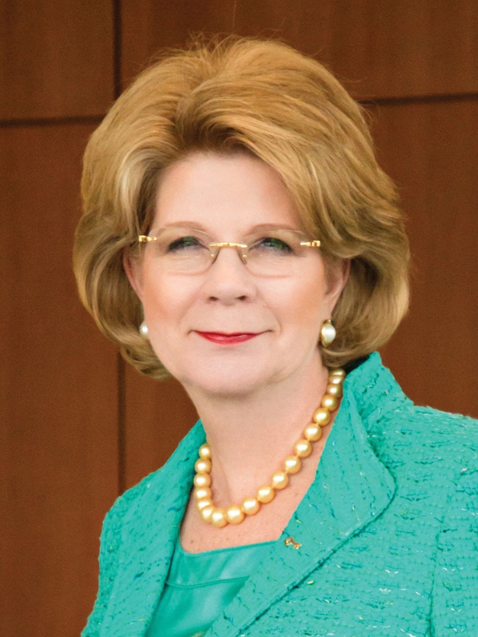 Beth Mooney, in a boardroom, smiles to camera