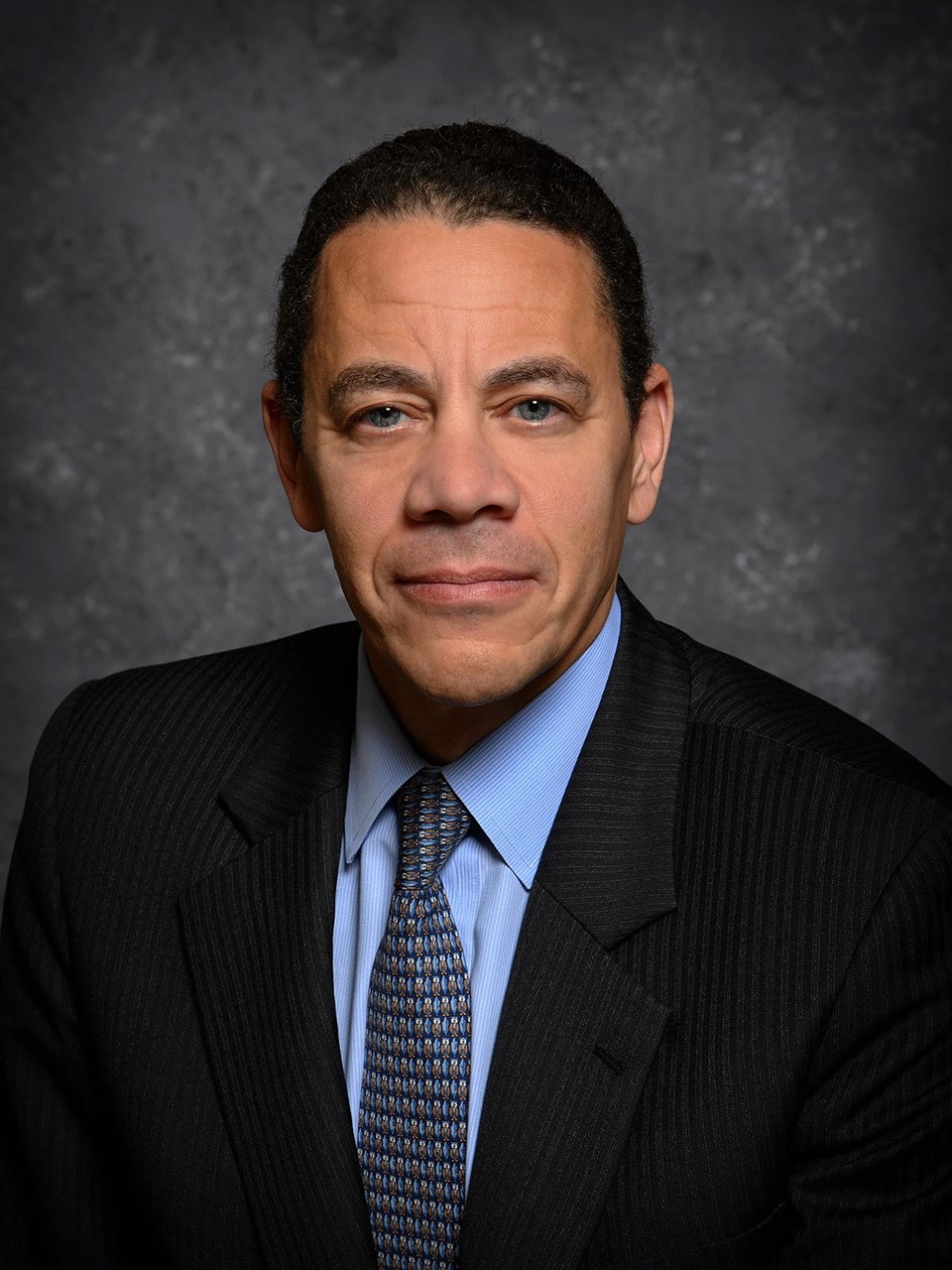 William Kennard, in a studio, smiles to camera