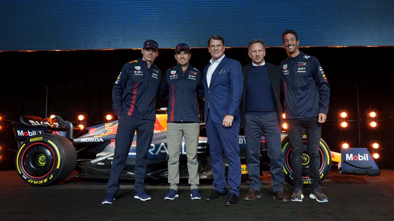 Jim Farley and a group of men are standing next to a Ford race car
