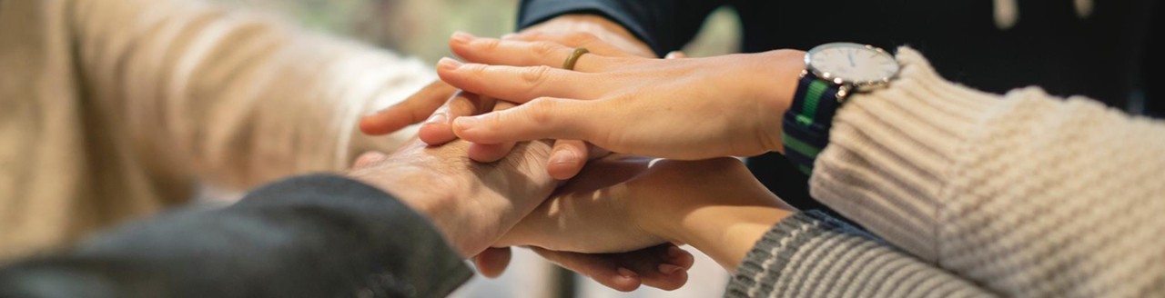 four people putting hands in