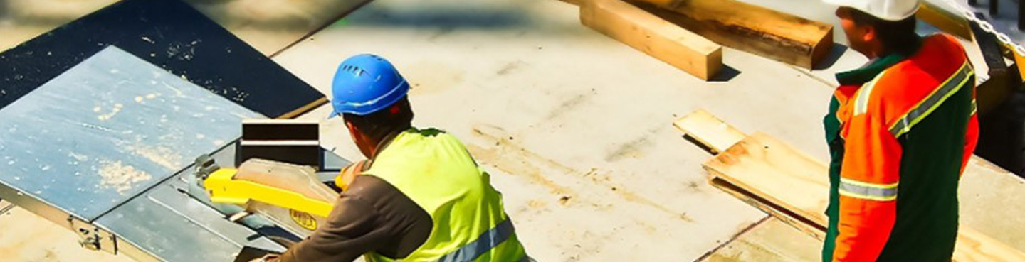 two construction workings working on roof with table saw and wood