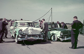A group of men looking at two vehicles that crashed