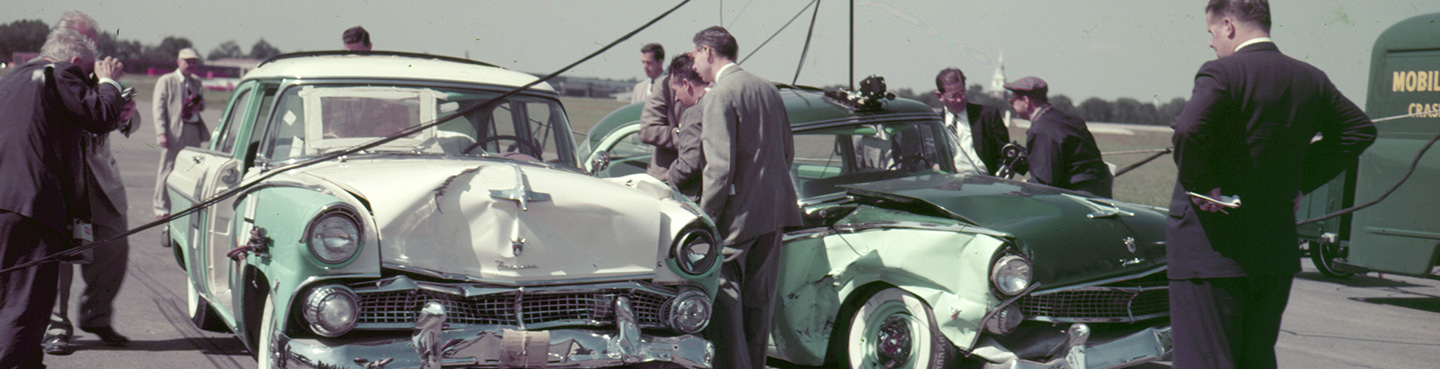 A group of men looking at two vehicles that crashed