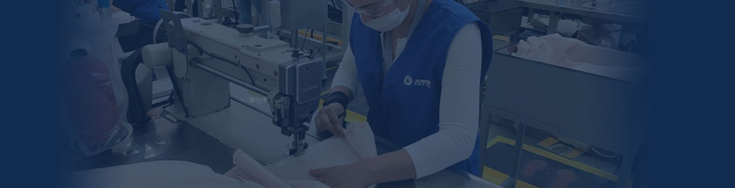 A female Ford employee sewing a protective gown with a sewing machine