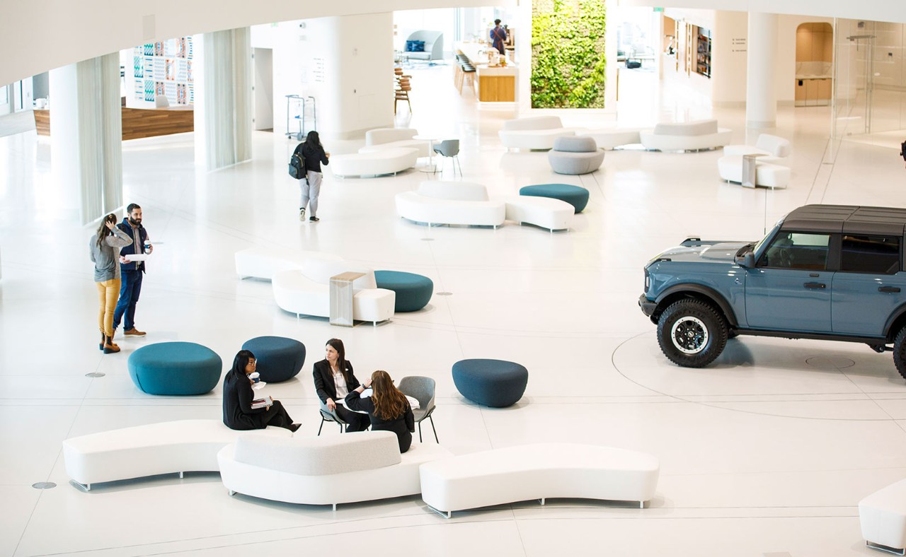 A female Ford employee and male Ford employee sitting together and looking at a laptop smiling