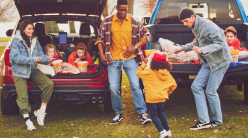 Two families enjoying snacks together with the children relaxing in the back of two parked Ford vehicles