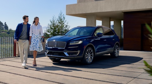 Couple walking past a Ford Lincoln