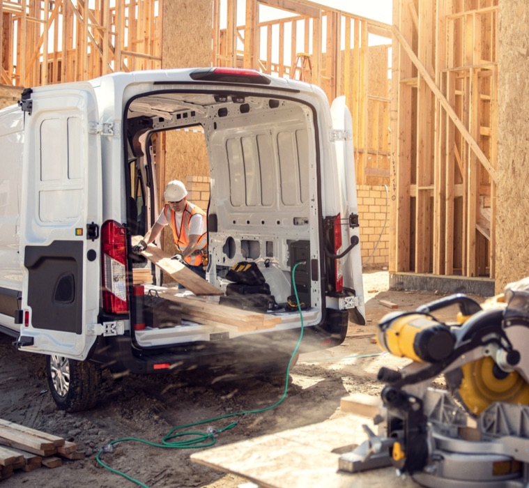 Worker powering tools using power cable from the New Ford E-Transit on a construction site