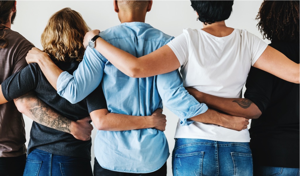 A diverse group of people with arms around each other