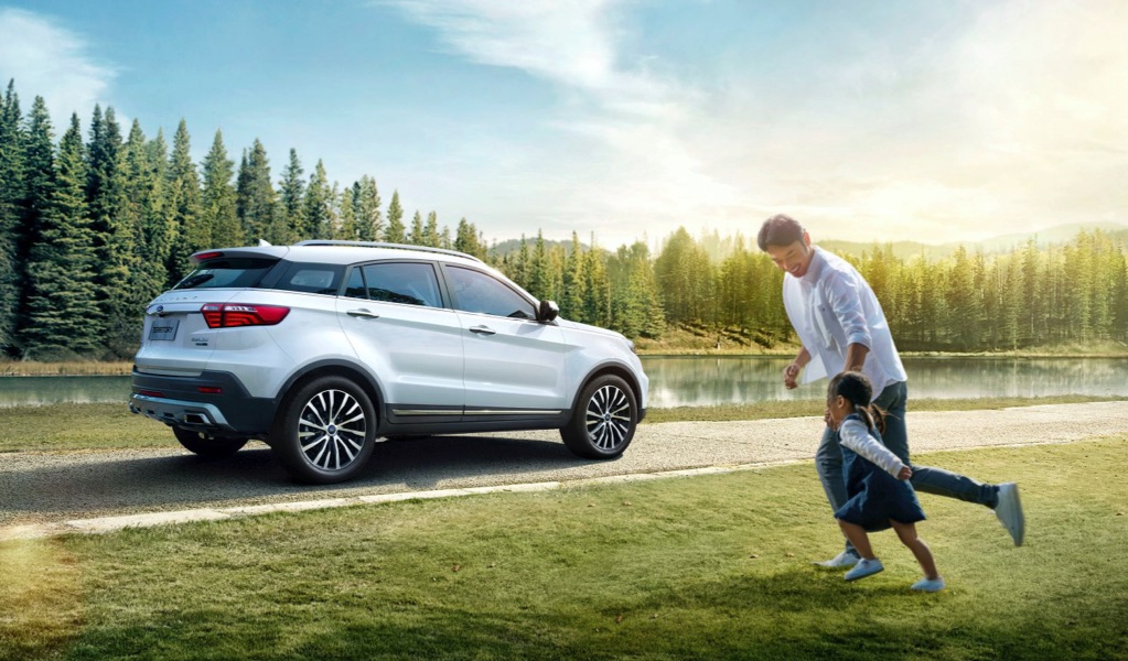 Father and daughter running freely across the grass to a parked Ford vehicle