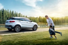 Man and child running across grass to a parked Ford vehicle