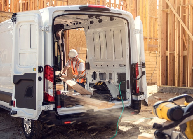 Worker powering tools using a power cable from the new Ford E-Transit on a construction site