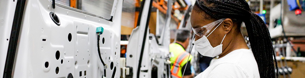 People working on vehicle doors on assembly line