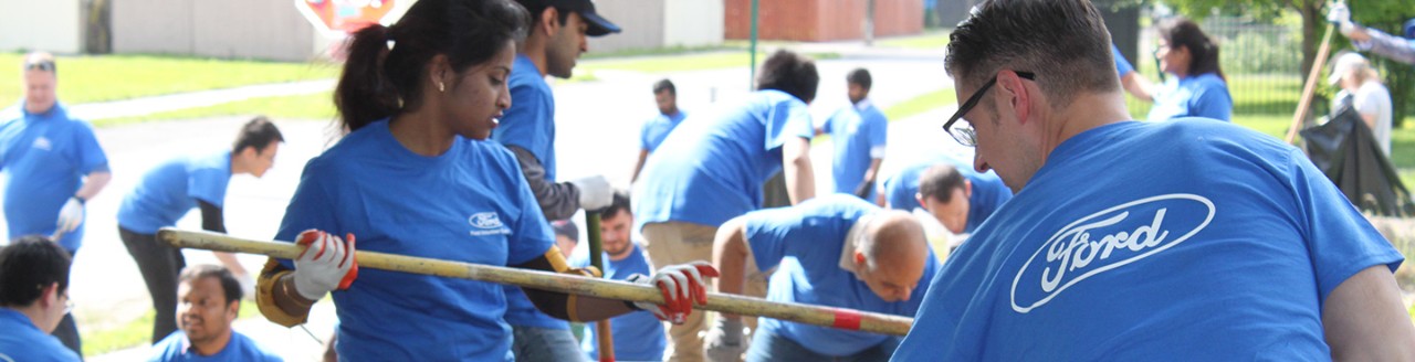 Image of people in Ford shirts using hand tools at a volunteer event