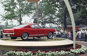 A red 1965 Mustang car on a display platform